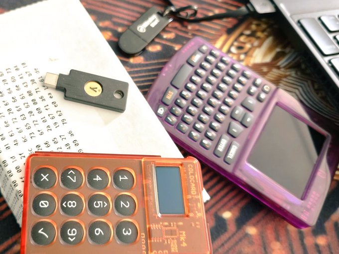 The image features two electronic devices - an orange calculator with buttons and a black USB drive. The calculator has a screen displaying numbers and symbols, while the USB drive appears to be connected to something else. A note or paper is also present on the surface where these items are placed. The text in the image seems to be related to Bitcoin or cryptocurrency, possibly discussing the importance of updating one's setup for better security and understanding.