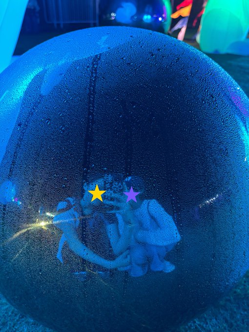 A blue-lit bubble bath with a rubber duck visible through the soapy surface, with yellow and purple star emoji markings covering the duck's eyes.