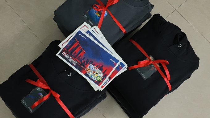 Folded black clothing items are bundled with red ribbons, accompanied by printed cards with a "Midnight Summit" design.