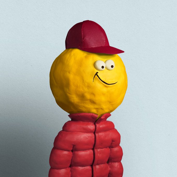A sculptural figure featuring a round yellow head with a smiling face and googly eyes, wearing a red baseball cap and a red puffer jacket.