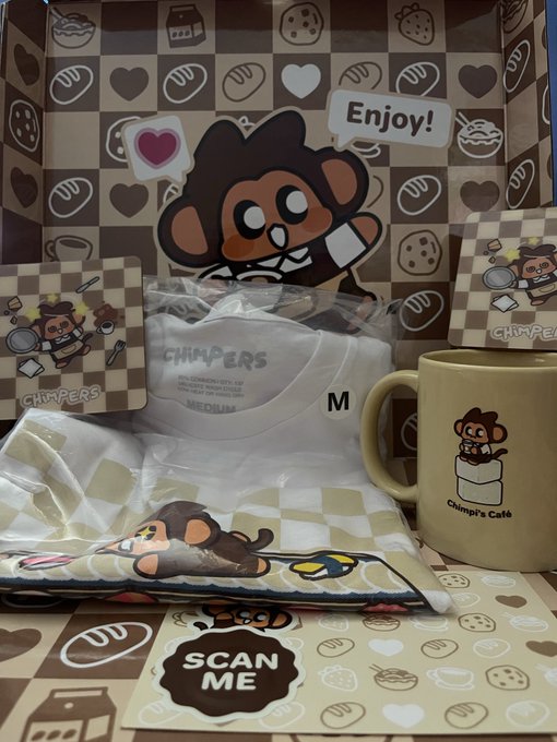 A 'Chimpe's Café' merchandise box containing a t-shirt, mug, sticker, and other items featuring a cartoon monkey mascot.