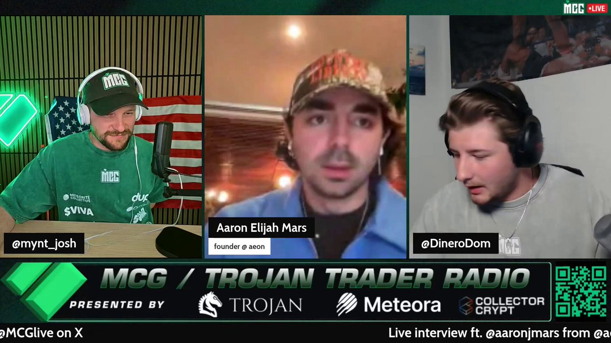 The image shows a screen with three men wearing hats, each holding a microphone. They are participating in an interview or discussion about cryptocurrency trading. The background of the image features a green color scheme, which complements the overall theme of the post on MCG's website.