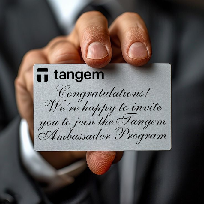 A hand holds up a white card reading "Tangem — Congratulations! We're happy to invite you to join the Tangem Ambassador Program," symbolizing the creator's official invitation into the Tangem brand ambassador community.
