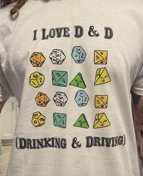A person wears a light gray t-shirt featuring colorful illustrated dice and the text 'I LOVE D & D (DRINKING & DRIVING)'.