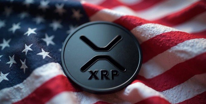 A black XRP coin rests on a draped American flag, visually reinforcing the post's bold claim that XRP could surge to $2,000 by 2026 according to Jake Claver's prediction.