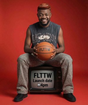 The image features a man sitting down, holding a basketball in his hands while wearing a tank top with the word "Lit" written across it. The man appears to be smiling for the camera. In front of him, there are two TVs - one is black and the other is white. Below these TVs, there's text that reads: "FLTTW launch date 4pm". This suggests that the man might have received a new outfit as a gift or won an event related to basketball, and he is sitting down while holding his basketball in front of the TVs.