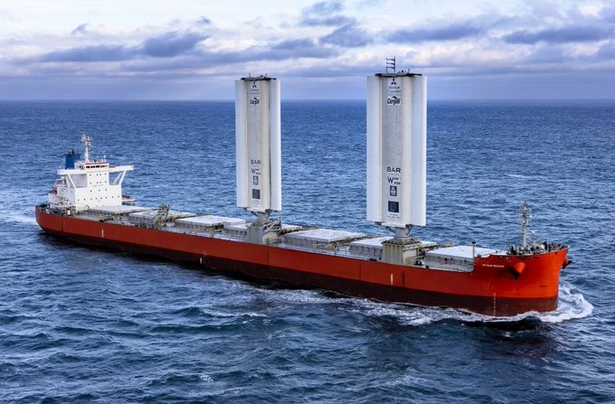 A large red cargo ship labeled 'PYTHON OCEAN' sails across the ocean, equipped with two tall white BAR Technologies wind propulsion sails.