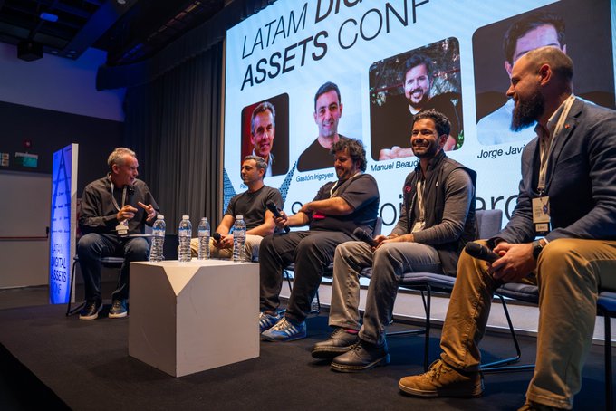 A panel discussion titled "LATAM DIGITAL ASSETS CONF" takes place on stage, featuring Pablo Wende interviewing Gaston Irigoyen, Manuel Beaudroit, Jorge Javier Eguino, and Santiago Maiztegui about connecting cards with digital assets, with their headshots displayed on the large screen behind them.