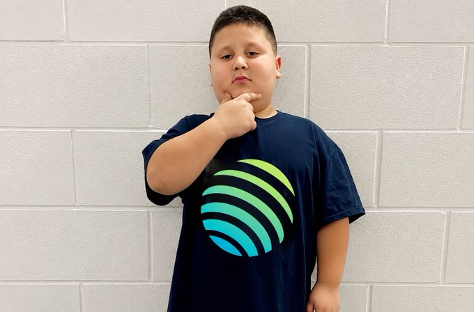 A young boy poses thoughtfully against a white brick wall, wearing a navy blue t-shirt featuring the Algorand (ALGO) logo, channeling a contemplative "thinking" pose. The image ties to the post's bullish sentiment ("Q3 is going to be big. wagmi.") by visually conveying careful consideration and optimism about Algorand's upcoming third-quarter performance.