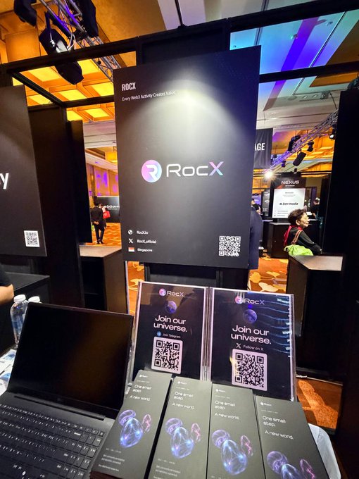 A booth display for RocX at an event, featuring promotional materials with QR codes and the tagline 'Join our universe,' along with 'Every Web3 Activity Creates Value.'