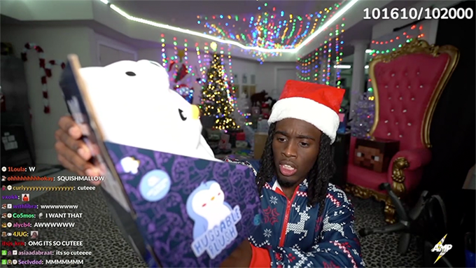 A livestream scene shows a man wearing a Santa hat and a Christmas-patterned hoodie holding up a laptop, with chat messages including "SQUISHMALLOW" and "cuteee" scrolling on the left side.