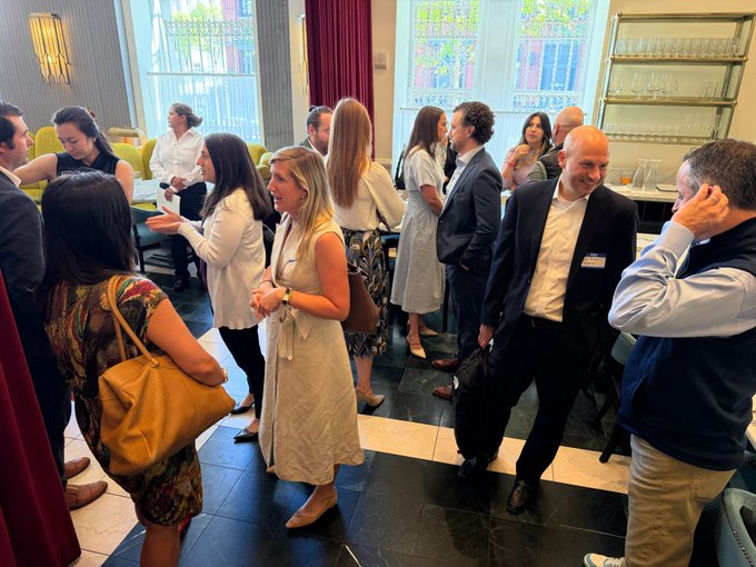 A group of professionals in business attire mingle and converse at what appears to be a corporate networking event, likely the WalletConnect policy roundtable with Cross River Bank and the Digital Chamber referenced in the post, featuring leaders from major crypto and tech companies like Circle, Ledger, and Fireblocks.