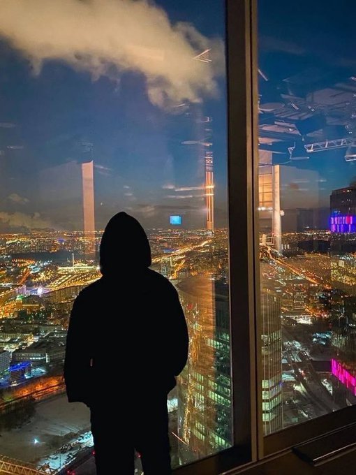 A hooded figure stands silhouetted against a sweeping nighttime cityscape viewed through a high-rise window, with glowing skyscrapers, highways, and clouds illuminated by city lights below.

The image pairs with the Ethra Ship post to visually evoke the concept of large-scale global infrastructure and logistics, mirroring the project's mission of connecting real-world shipping operations to blockchain technology—turning tangible cargo movement into verifiable on-chain activity.