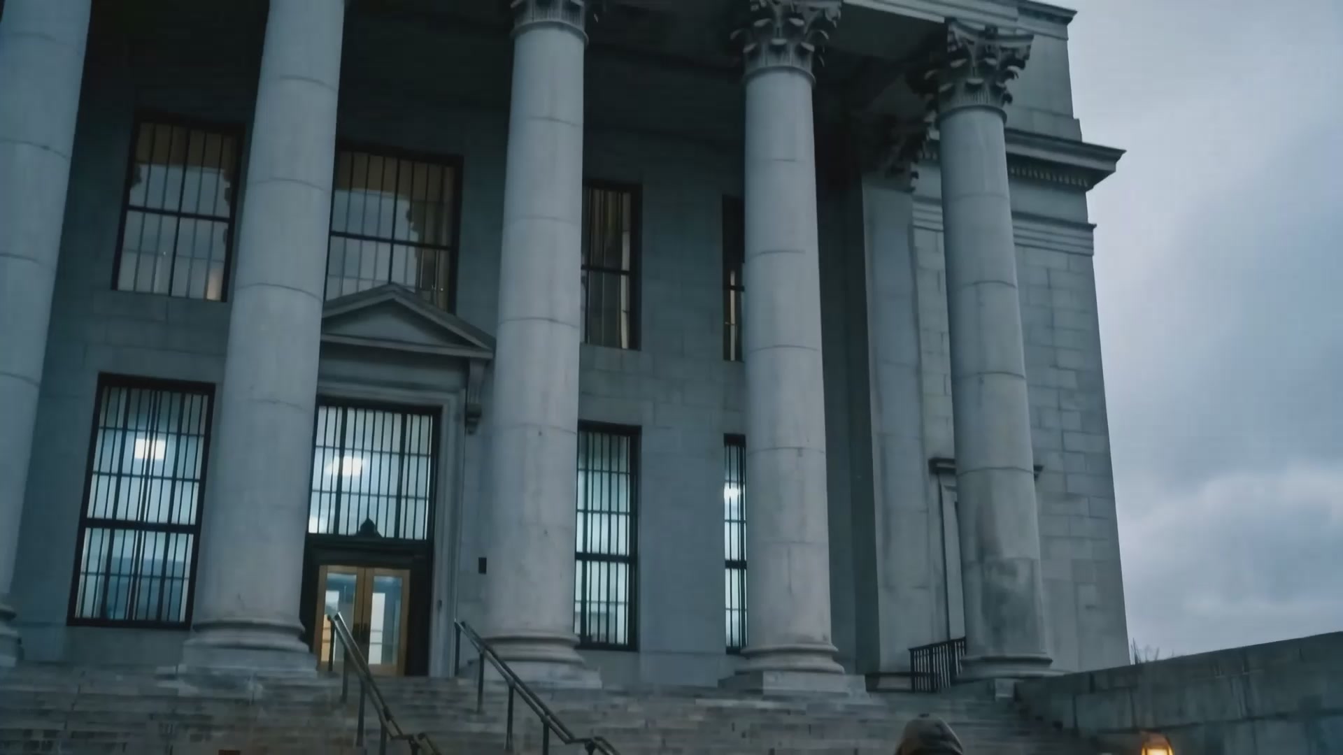 The image shows an old, large building with columns and a staircase leading up to the entrance. There are no people or other objects visible in the scene. The focus of the image is on the architectural features of the building, such as its columns and stairs.