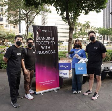Four people, including two wearing BingX-branded shirts, pose outdoors in Jakarta alongside a "BingX Charity" banner reading "STANDING TOGETHER WITH INDONESIA," with one person holding a BingX tote bag—visually supporting the post's message about the Indonesia team's on-the-ground community efforts.