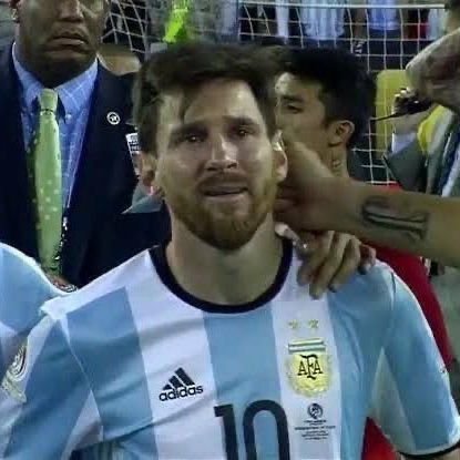 A close-up photo of soccer player Lionel Messi wearing the Argentina national team jersey with number 10, appearing emotional after a match.