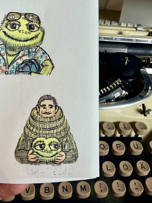 A close-up photo showing hand-drawn illustrations of quirky characters (one labeled 'vice') on a notepad resting on the keyboard of an old typewriter with diacritic-marked keys.