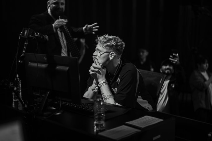 A competitor intently watches a screen with hands clasped, likely focused on high-stakes trading action at Solana's event in Korea. The "10" logo on his shirt and the dramatic black-and-white lighting capture the intensity of the 100x leverage trading competition referenced in the caption.