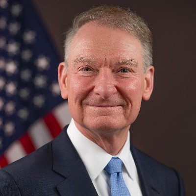 A formal portrait of SEC Chairman Paul Atkins, shown wearing a dark suit with a light blue tie, standing in front of an American flag. The image accompanies his statement pledging decisive SEC action to provide regulatory certainty for investors and tech entrepreneurs.