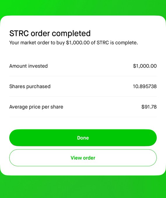 This image displays a screen with green text and numbers against a brown background, likely providing information about an order completed for $1,000 of STCR shares at a price of $91.78. The text mentions that this is the worst sentiment I've seen around Saylor / Strategy yet it's still worth taking the bet on this particular market trend, as indicated by the 12.5% yield expected upon executing the order.