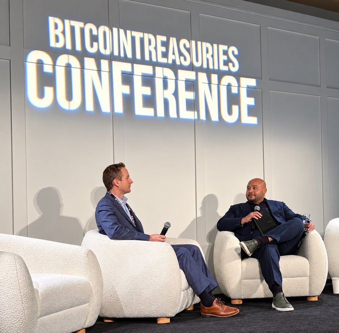 Two men in suits engage in a fireside chat on stage at the "BITCOINTREASURIES CONFERENCE," with the post highlighting BlackRock's influential vision for Bitcoin. The professional setting and discussion format suggest a high-level dialogue about institutional Bitcoin adoption and treasury strategies.