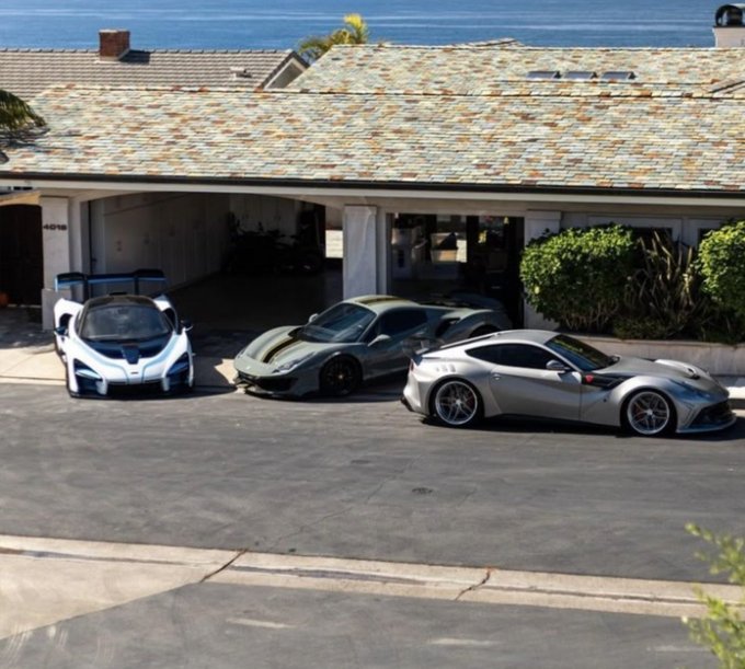 Three high-performance sports cars—a white Ferrari FXX, a dark gray Ferrari Pista, and a silver Ferrari F12tdf—are parked in the driveway of a coastal home, likely in Connecticut ("CT"), with the ocean visible just beyond the rooftop. The post "Good morning CT" suggests a casual greeting showcasing the owner's impressive Ferrari collection on a sunny morning by the sea.