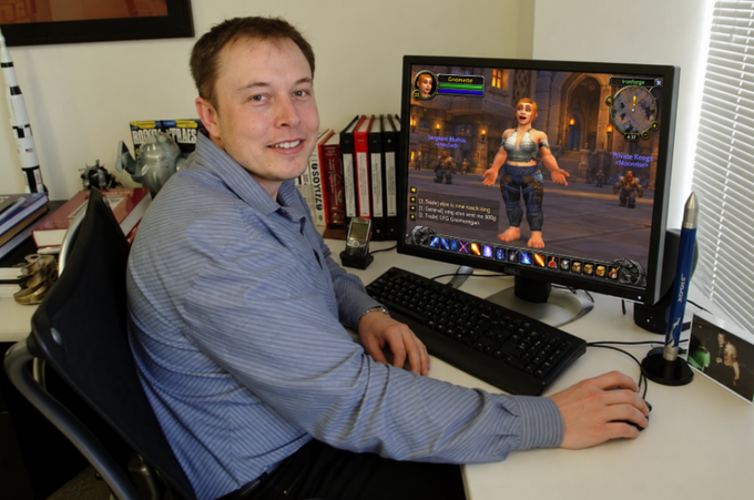 A man sits at a desk smiling at the camera while using a computer that displays the World of Warcraft game, with a rocket pen holder visible on the desk.