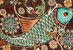 An intricate decorative artwork or textile featuring a stylized turquoise fish surrounded by floral patterns and a small bird.