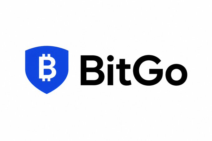 The image features a logo for a company named BitGo, which is an online currency exchange platform based in Dubai. The logo consists of a shield with the word "BITGO" written inside, surrounded by blue text that reads "Bits Go". This logo represents the company's focus on digital assets and their expansion into various aspects of the financial industry beyond traditional custody services.