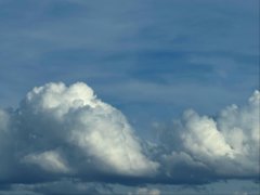 A scenic view of fluffy white clouds against a clear blue sky.