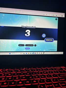 A laptop with a red-backlit keyboard displays a webpage showing "You Revealed 3" with a "D MON" badge.