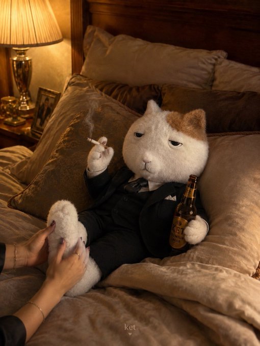 A realistic image of a chubby white and orange cat dressed in a black suit, smoking a cigarette and holding a beer bottle while someone massages its paw on a bed.