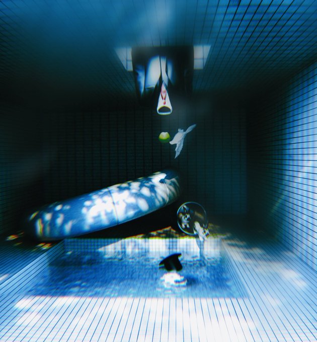 An abstract blue-tinted image shows a surreal composition with a cylindrical object, a small floating figure, and light reflections on a gridded surface.