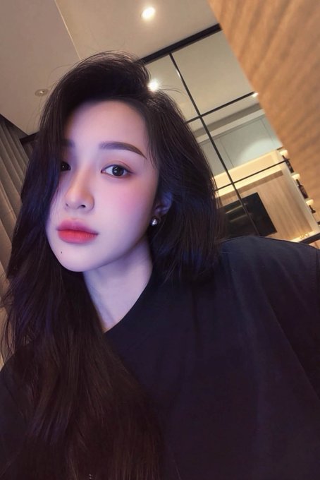 A young woman with long dark hair takes a close-up selfie in what appears to be a modern interior, wearing a dark top and looking directly at the camera with a neutral expression. The image accompanies a celebratory post about receiving a "PayX" payout, likely serving as a personal photo to connect with the community of followers sharing in the earnings milestone.