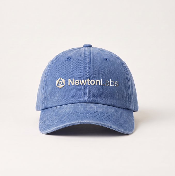 A faded blue denim dad cap featuring the embroidered "NewtonLabs" logo sits on a white surface. The cap's worn, vintage look ties into the "cooked or cooking?" caption, suggesting it has been baked in the sun to achieve its washed-out, weathered appearance.