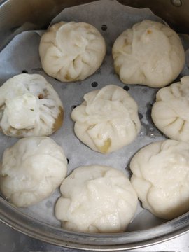 Steamed pork buns (baozi) arranged in a bamboo steamer, made by the author's wife as a free breakfast treat. The post celebrates a streak of self-discipline while noting that unlike the previous crypto bear market when he had to stretch every dollar to dollar-cost average into BTC, this cycle he can buy the dip comfortably with profits from US stocks — all thanks to Binance.