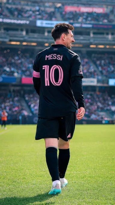 A soccer player wearing a black jersey with "MESSI" and the number "10" in pink stands on the field with his back to the camera, set against a packed stadium crowd. The image doesn't directly relate to the post about the Nomisma Network campaign, creating a thematic disconnect between the sports imagery and the cryptocurrency promotion.