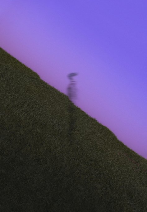 A blurry figure runs up a grassy hill silhouetted against a purple and blue twilight sky.