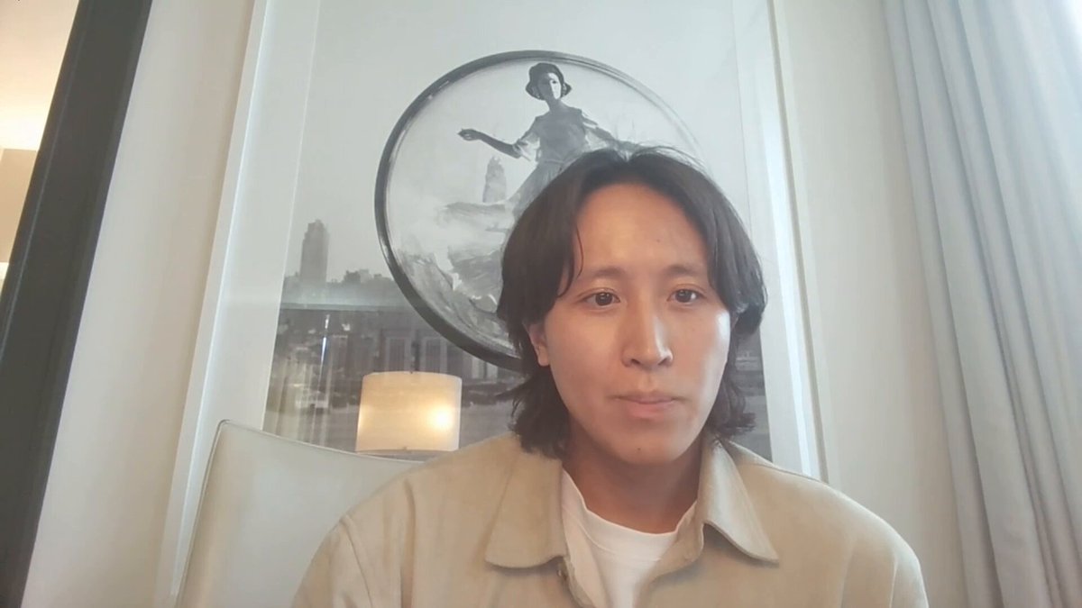 The image shows Andrew Kang sitting down with his head tilted back while looking directly into the camera. The background features a large picture of a woman, which appears to be a painting or an abstract art piece. The caption below the picture reads "People within the crypto space think Bitcoin'S the world and it'S a big asset, but SpaceX is now bigger than Bitcoin." This statement seems to be related to the image's content, as Andrew Kang might have made a statement about the size of Bitcoin compared to other assets or the value of Bitcoin in relation to space exploration.

The image also contains several objects such as a chair and a lamp, which are placed around the room. The presence of these items suggests that this scene takes place in an indoor setting like a living room or a studio apartment.