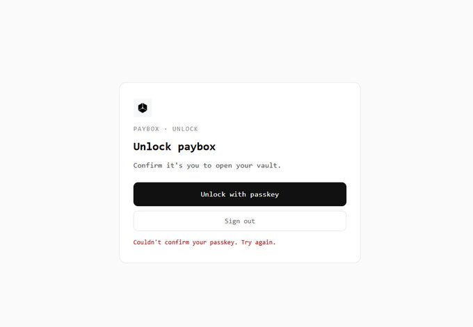 A minimalist 'Unlock paybox' confirmation screen prompts 'Confirm it's you to open your vault' with an 'Unlock with passkey' button and a 'Couldn't confirm your passkey. Try again.' error message in red.