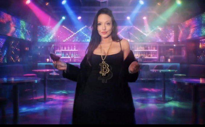 A woman in a black outfit wears a large Bitcoin "B" necklace while posing in a neon-lit nightclub, embodying the "Bitcoin Bull" theme referenced in the post about $TBB ticker. She holds a phone as if checking the market, fitting the caption's play on "buy low, sell high."