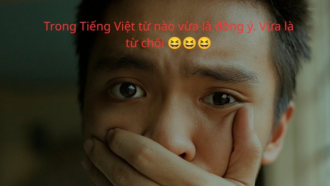 A close-up photo of an Asian man covering his mouth with his hand, with red Vietnamese text asking 'Trong Tiếng Việt từ nào vừa là đồng ý, vừa là từ chối' with laughing emojis.