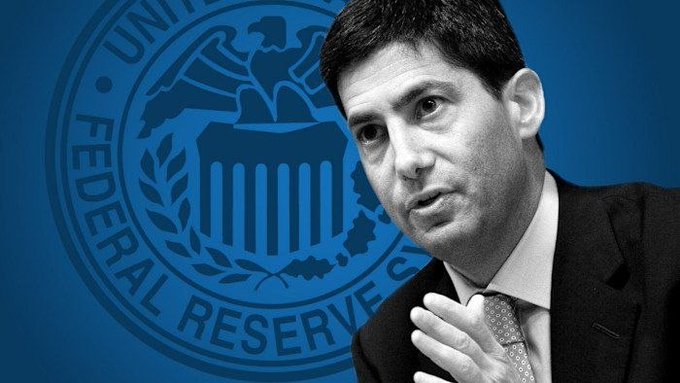 A man in a dark suit and tie is shown speaking, with the blue seal of the United States Federal Reserve System visible in the background, featuring the words "UNITED," "FEDERAL RESERVE," and a partial "S." His pensive expression and gesture relate to the breaking news of the U.S. CPI inflation report matching expectations at 3.4%, reflecting the Fed's ongoing focus on inflation data as it considers future monetary policy decisions.