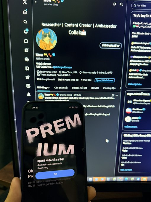 A smartphone displaying the word 'PREMIUM' over a Twitter/X profile of a crypto content creator/ambassador named 'Meow_web3', held in front of a monitor showing the same profile.