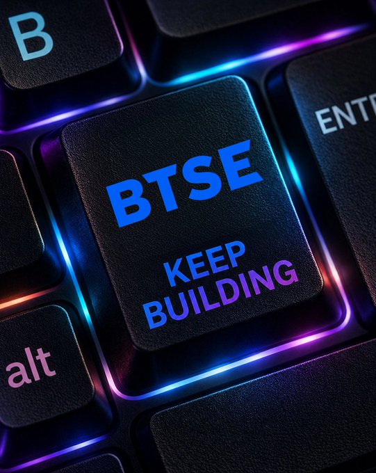 The image shows a close-up view of a computer keyboard with the word "BTSE" written on it, along with the phrase "Keep building". The focus of this image is on the keyboard keys, which are illuminated by colorful lights in various shades of blue and purple. This lighting effect emphasizes the importance of the message displayed on the keyboard: to keep building and not give up on trading crypto, US stocks, and commodities.