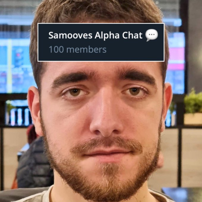 Close-up selfie of a young man with a Samooves Alpha Chat overlay showing 100 members, with monitors displaying charts visible in the background.
