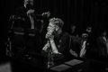 A dark, low-resolution image shows what appears to be a person in a theater or audience setting.