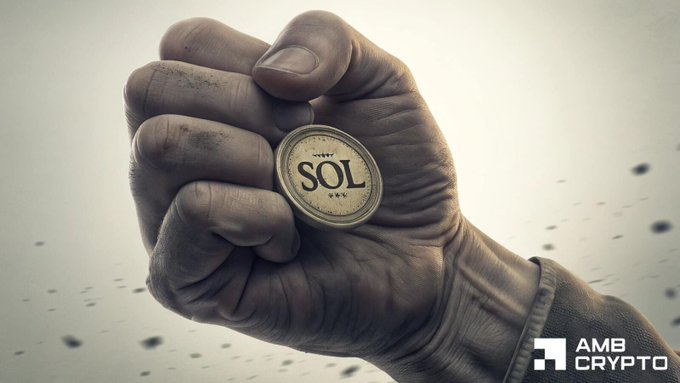A hand holding a silver coin with the word 'sol' written across its surface, indicating the coin is part of the Solana cryptocurrency network. The coin value is shown as $500,000,000 USDC, which signifies its worth in US dollars. Additionally, it was minted on the CoinMarketCap website and is available for purchase or exchange within the Bitcoin ecosystem.