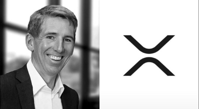 A black-and-white photo of a smiling man in a suit is shown next to the XRP cryptocurrency logo.