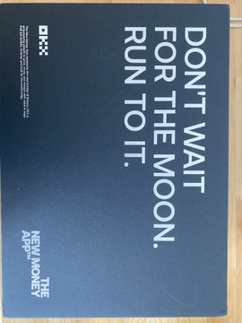 A dark blue book or notebook cover featuring the iconic 'DON'T WAIT FOR THE MOON. RUN TO IT.' quote and logo from NewJeans' 'NewJeans The ADE' merchandise.